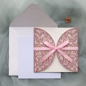 Détail de découpe laser motif floral sur invitation rose pailletée avec nœud satin