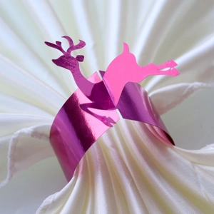 Macro detail of a laser-cut rose pink mirror-finish reindeer napkin ring for Christmas