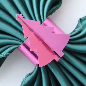 Détail d'un rond de serviette sapin de Noël rose miroir sur du satin vert foncé