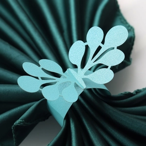 Close-up of light blue laser-cut pearlescent paper napkin ring with wing design