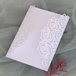 Detail of white laser-cut wedding invitation envelope with intricate rose patterns