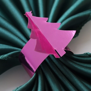 Détail du rond de serviette sapin de Noël rose miroir sur tissu en satin vert foncé