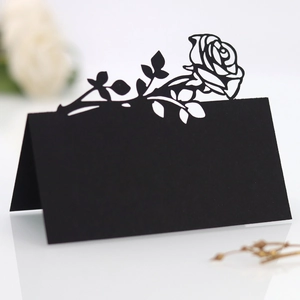 Macro detail of laser-cut black paper place card with intricate rose pattern