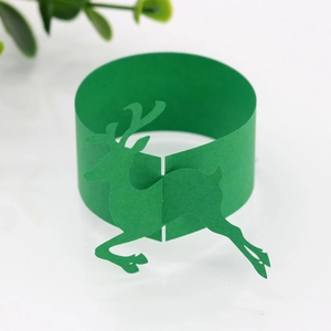 Detail showing laser-cut green paper napkin ring with running reindeer silhouette design