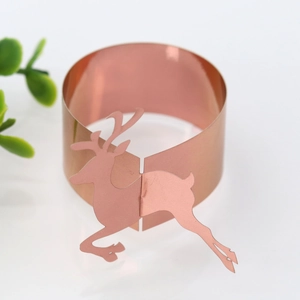 Macro detail of rose gold reindeer napkin rings made of reflective paper for festive dining