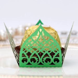 Detail showing green laser-cut lace candy wrapper with elegant crown patterns on tray