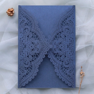 Close-up of navy blue laser-cut wedding invitation with fine glitter and lace detail