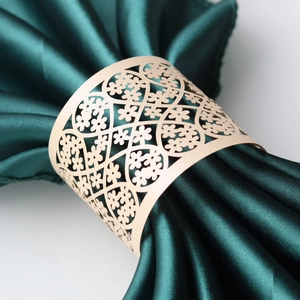 Detail of laser-cut gold lace napkin ring with floral pattern on dark green napkin