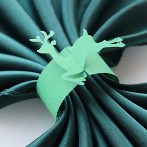 Detail of light green paper napkin ring featuring a laser-cut reindeer silhouette design