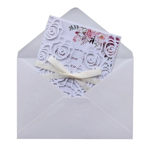 Detail of laser-cut rose invitation with white ribbon and floral printed insert card