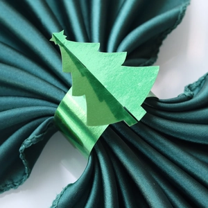 Gros plan du rond de serviette sapin de Noël vert sur un tissu en satin foncé