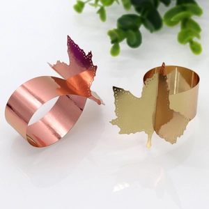 Close-up of golden and rose gold maple leaf napkin rings with hollow cut-out details