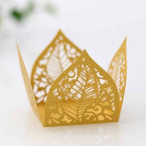 Macro shot of laser-cut gold pearlescent paper favor box with intricate leaf patterns