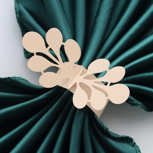 Detailed laser-cut pearl paper napkin ring with floral lace pattern on green fabric