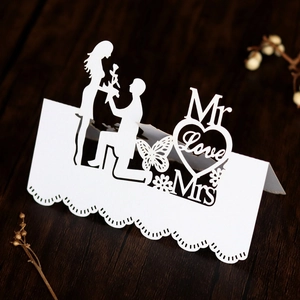 Close-up of laser-cut wedding place card with couple silhouette and heart details