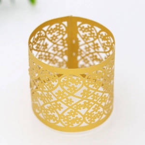Close-up of golden laser-cut paper napkin ring with intricate floral lace pattern