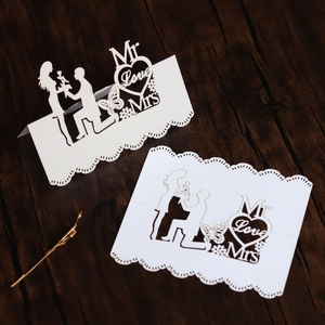 Laser cut white heart place card with Mr & Mrs Love silhouette on dark wood table