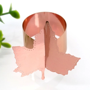 Macro shot of rose gold maple leaf paper napkin ring with elegant cutout details