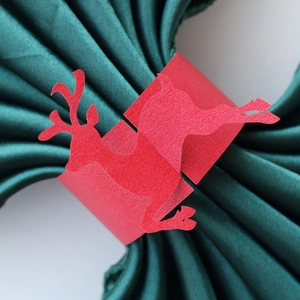 Detail of red Christmas reindeer paper napkin ring with glitter texture on green fabric