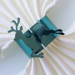 Close-up of a teal reindeer silhouette napkin ring on a white folded cloth