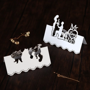 Detail of laser-cut white wedding place cards with Mr, Mrs silhouettes and Love heart