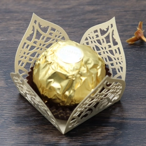 Macro detail of laser-cut petal wedding favor box with pearl paper and golden chocolate
