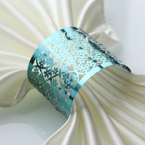 Elegant teal metallic laser-cut napkin ring with floral lace pattern on white satin