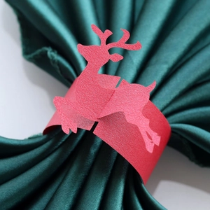 Macro view of red elk pearlescent paper napkin ring on green silk fabric for Christmas