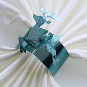 Close-up of a teal metallic reindeer napkin ring with laser-cut Christmas elk design