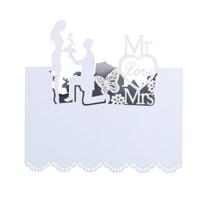 Detail of laser-cut white heart wedding place card with butterfly and floral patterns