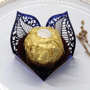 Macro view of laser-cut blue leaf pattern hollow chocolate wrapper for wedding party