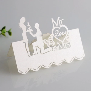 Macro detail of laser-cut pearl white wedding place card with heart and butterfly motifs