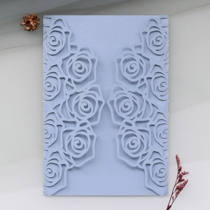 Detailed laser-cut light blue pearlescent paper wedding invitation with rose pattern