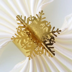 Macro shot of a golden hollow snowflake napkin ring on a white fabric napkin