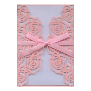 Intricate laser-cut pink rose wedding invitation card with a matching silk ribbon bow
