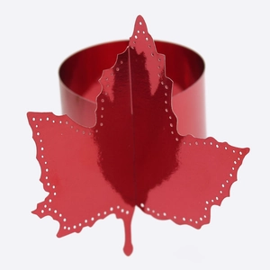 Close-up of red maple leaf napkin ring with intricate hollowed edges and metallic finish