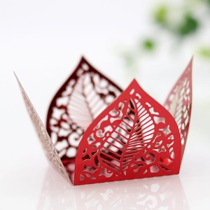 Macro view of laser-cut red paper candy box with hollow leaf patterns and artistic texture
