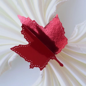 Detail of red maple leaf napkin ring with metallic finish on white textured fabric
