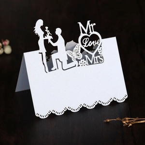 Detailed laser-cut white wedding place card featuring elegant silhouettes and floral patterns