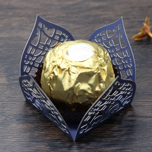 Detail of dark blue laser-cut paper chocolate box with delicate lace pattern and gold foil candy