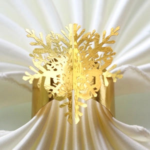 Macro detail of high-shine gold snowflake napkin ring with intricate hollow engraving