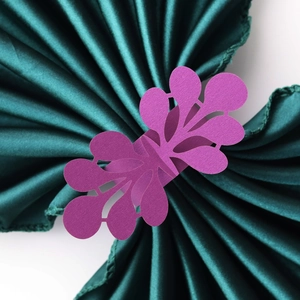 Close-up of purple laser-cut paper napkin ring with intricate floral lace pattern