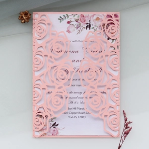 Detailed laser-cut rose pattern on pink wedding invitation with floral printed inner card