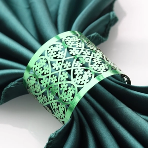 Detail of green metallic napkin ring with intricate hollow floral lace patterns
