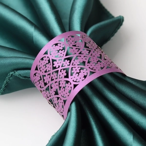 Purple pearl paper napkin ring with laser-cut floral filigree on dark green satin fabric
