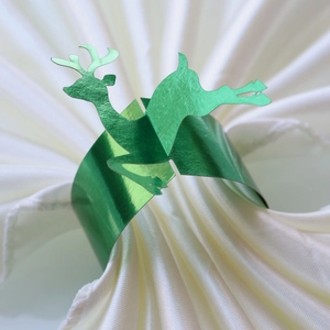 Close-up of a green metallic reindeer paper napkin ring on a white napkin