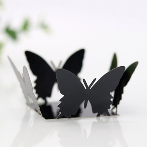 Close-up of laser-cut black butterfly decorations with 3D folding effect on white surface