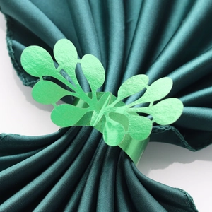 Close-up of light green hollow leaf paper napkin ring with elegant laser-cut pattern