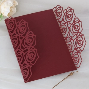 Macro detail of laser-cut burgundy rose invitation sleeve on elegant white tulle background