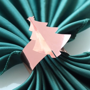 Gros plan du rond de serviette sapin de Noël or rose sur tissu vert foncé
